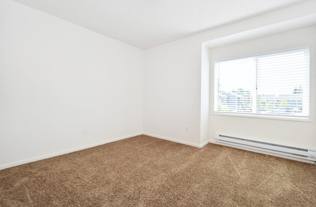 a bedroom with a large window and a carpeted floor