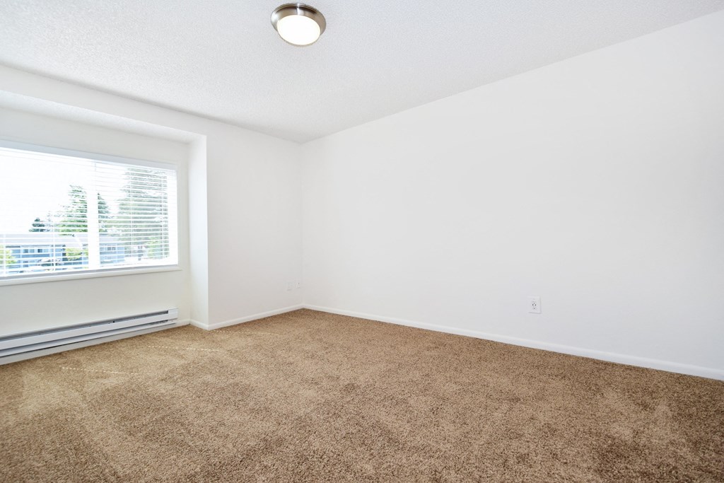 a bedroom with a large window and a carpeted floor