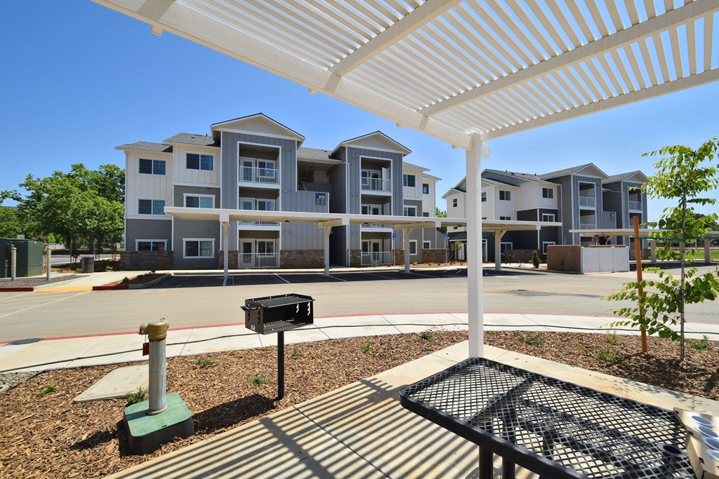 a picnic table with a grill and a grill grate in front of an apartment complex