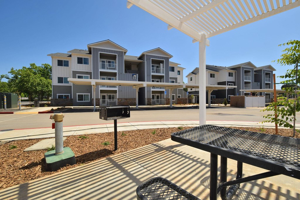 a patio with a picnic table and grill at the whispering winds apartments in pearland, tx