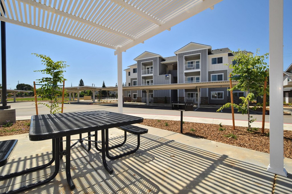 a patio with a picnic table and awning at the whispering winds apartments in pearland