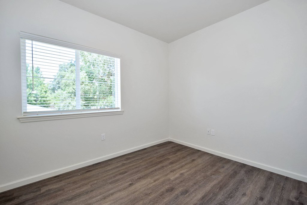 a bedroom with white walls and a large window