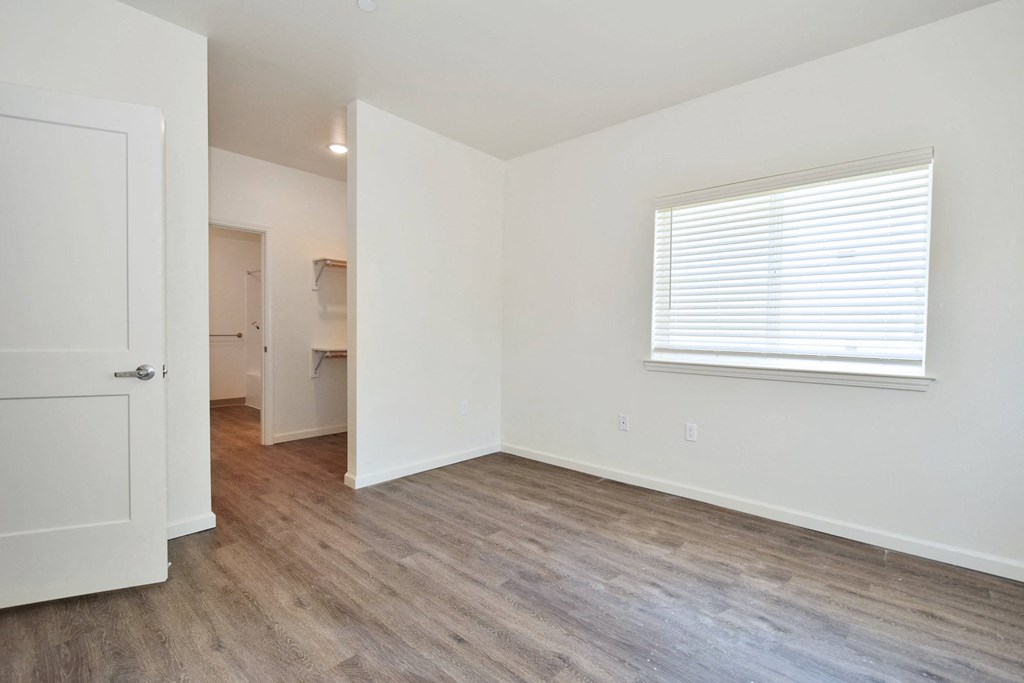 a bedroom with hardwood floors and white walls