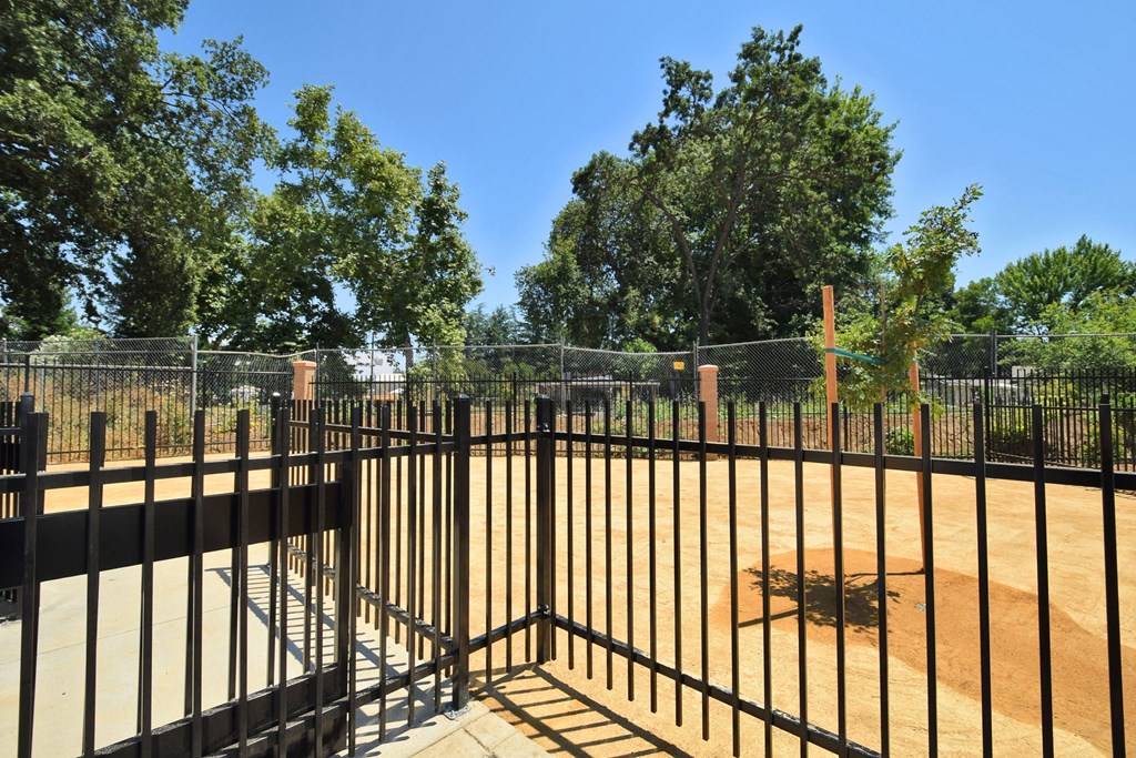 a fence in a park with trees in the background