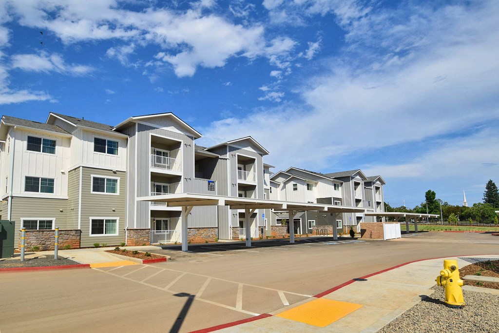 a row of apartment buildings with a parking lot and fire hydrant in the foreground