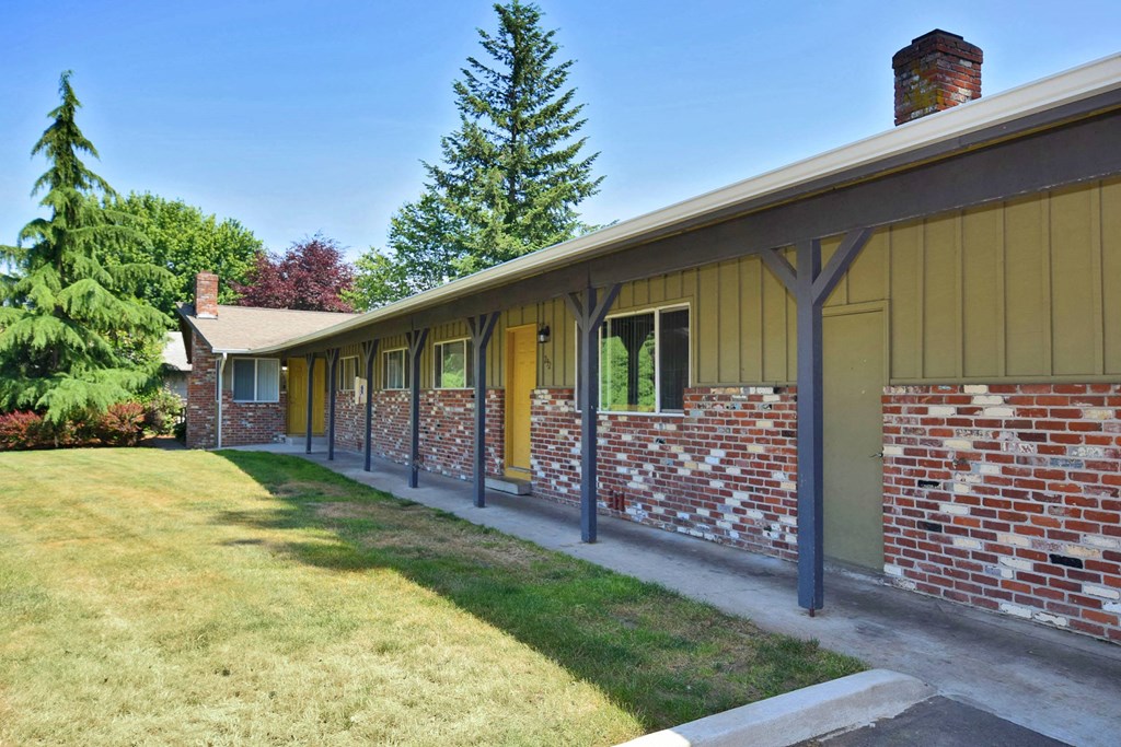 a long building with a grassy area in front of it and trees in the background