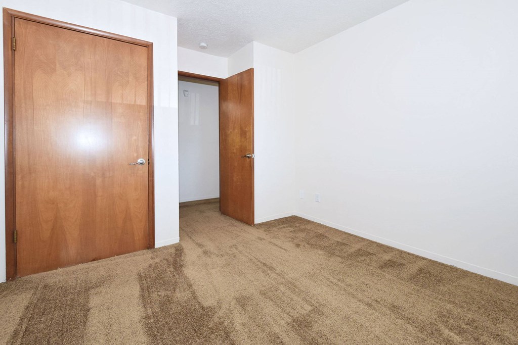 a bedroom with white walls and a brown carpet