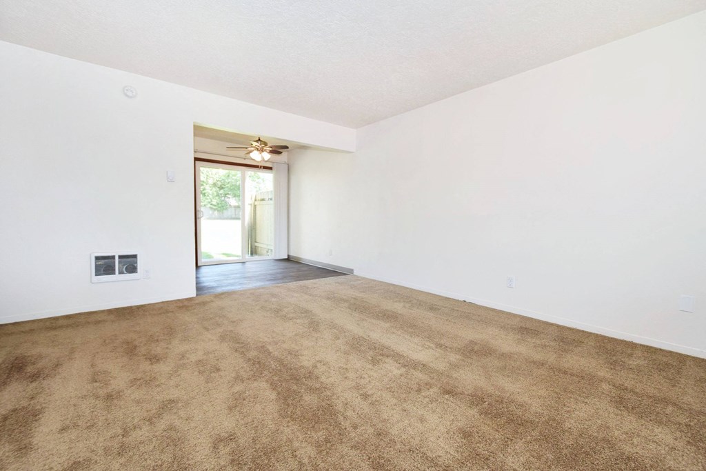 a living room with white walls and a beige carpet