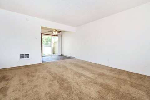 the spacious living room with white walls and a carpeted floor