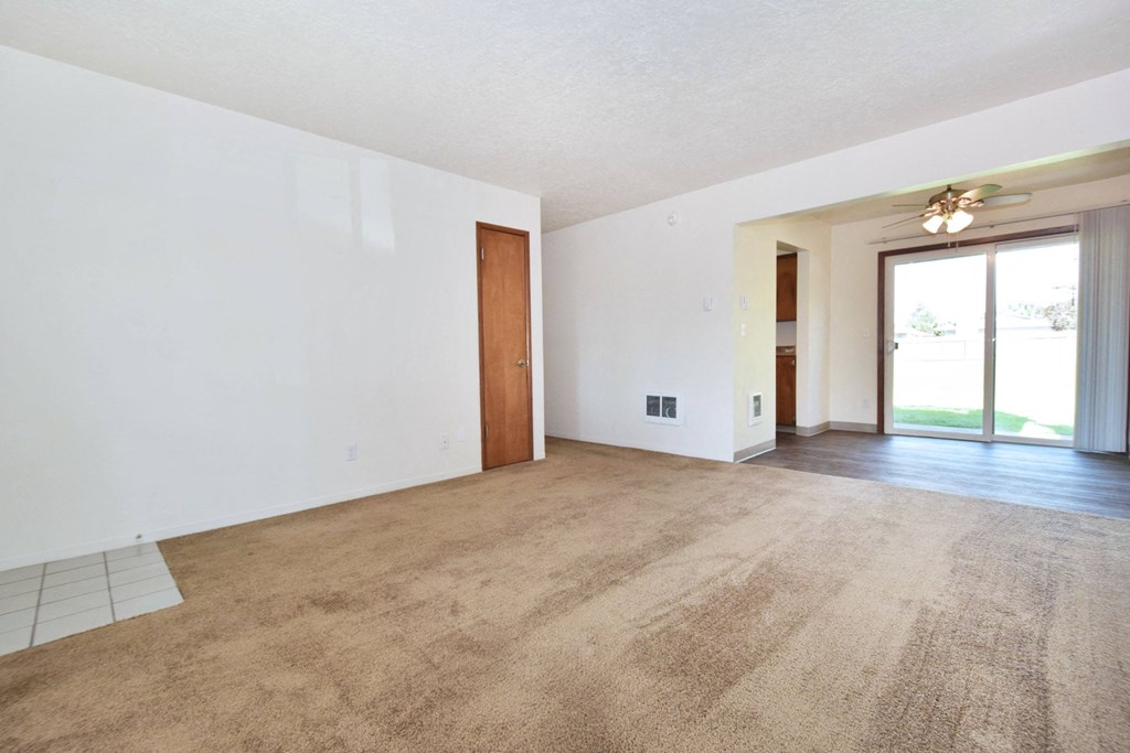 an empty living room with white walls and carpet