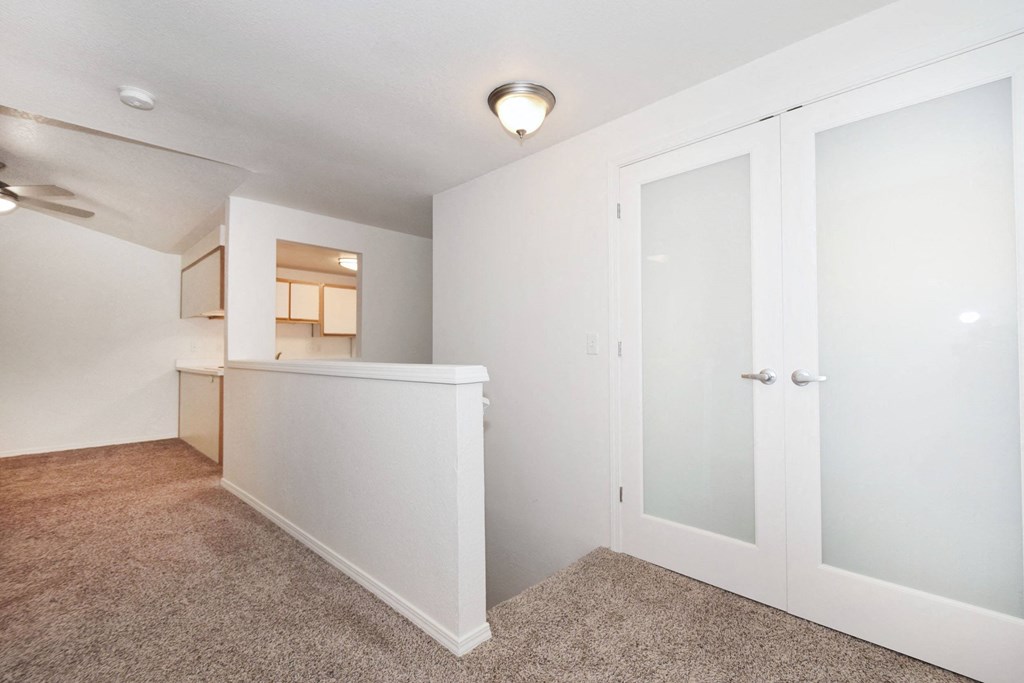 a renovated living room with white walls and a door to a kitchen