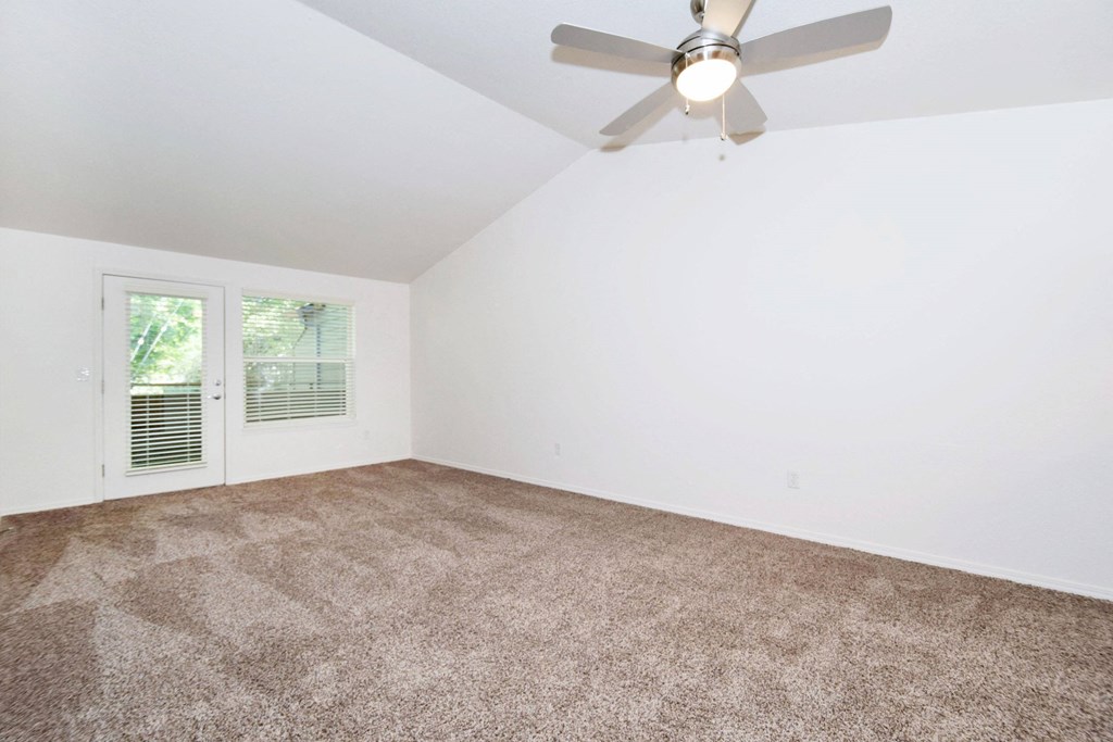 an empty living room with a ceiling fan and a window