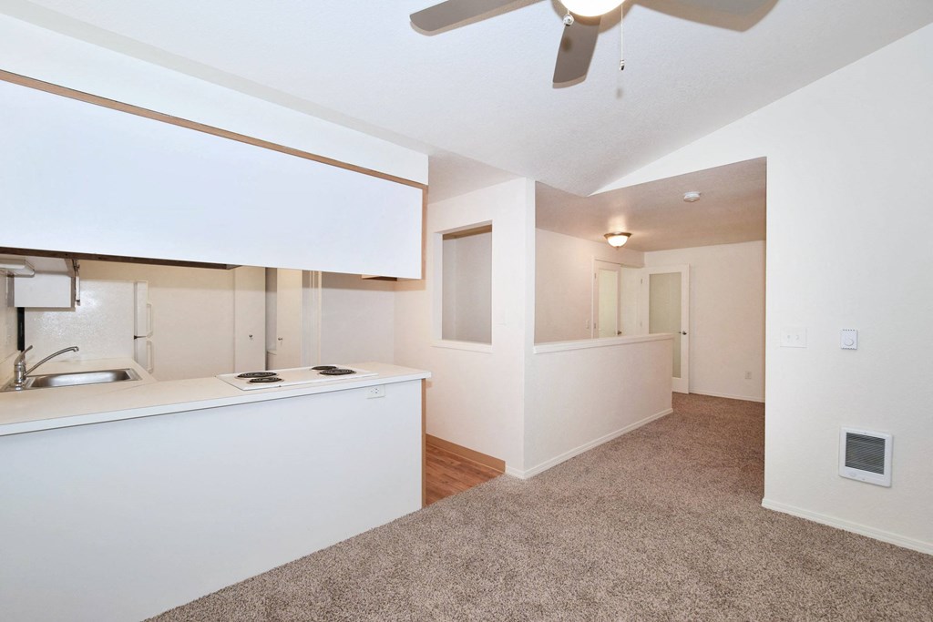 a renovated living room with a kitchen and a ceiling fan