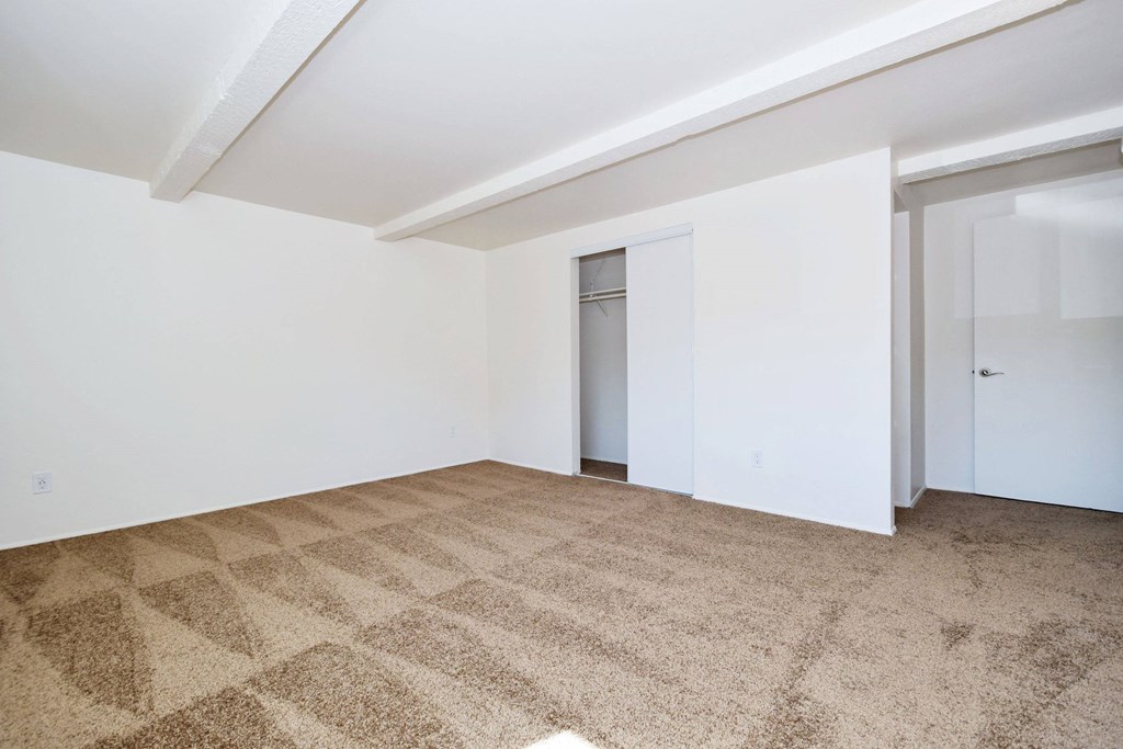 a bedroom with white walls and a beige carpet