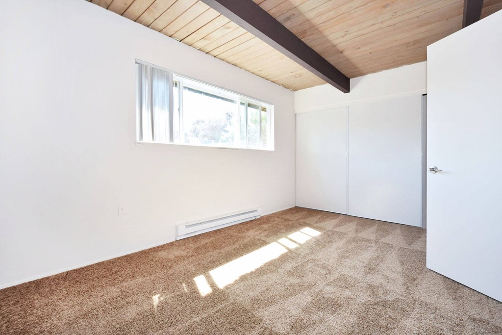 a bedroom with white walls and a window