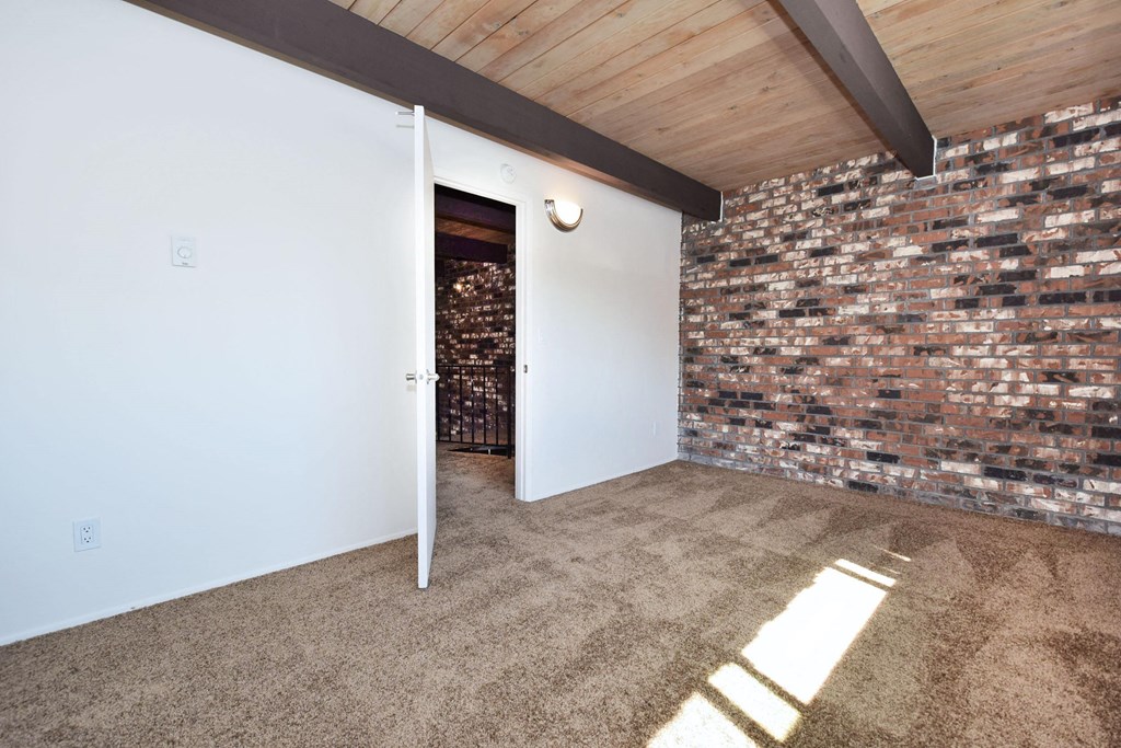 a white door leads into a white room with a brick wall