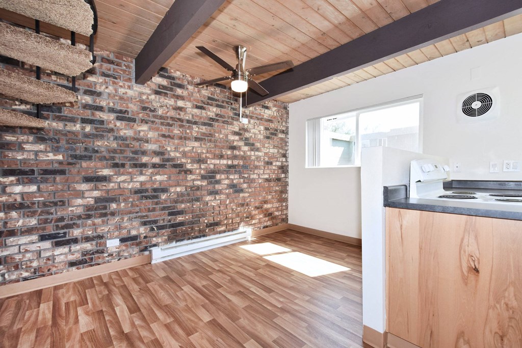 an open kitchen and living room with hardwood floors and a brick wall