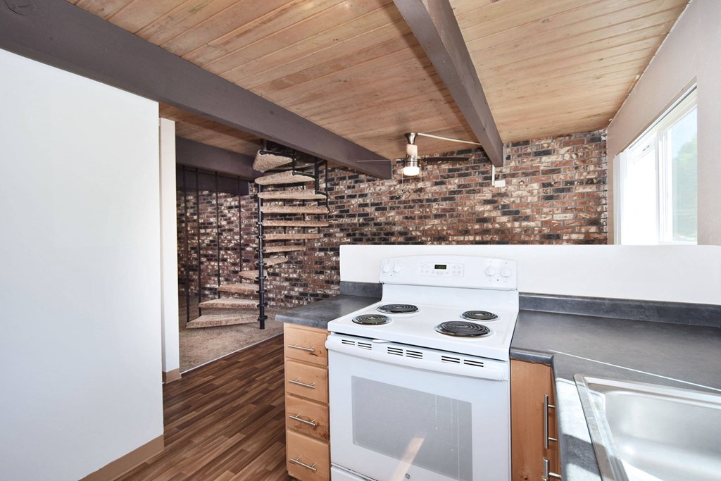 a kitchen with white appliances and a brick wall