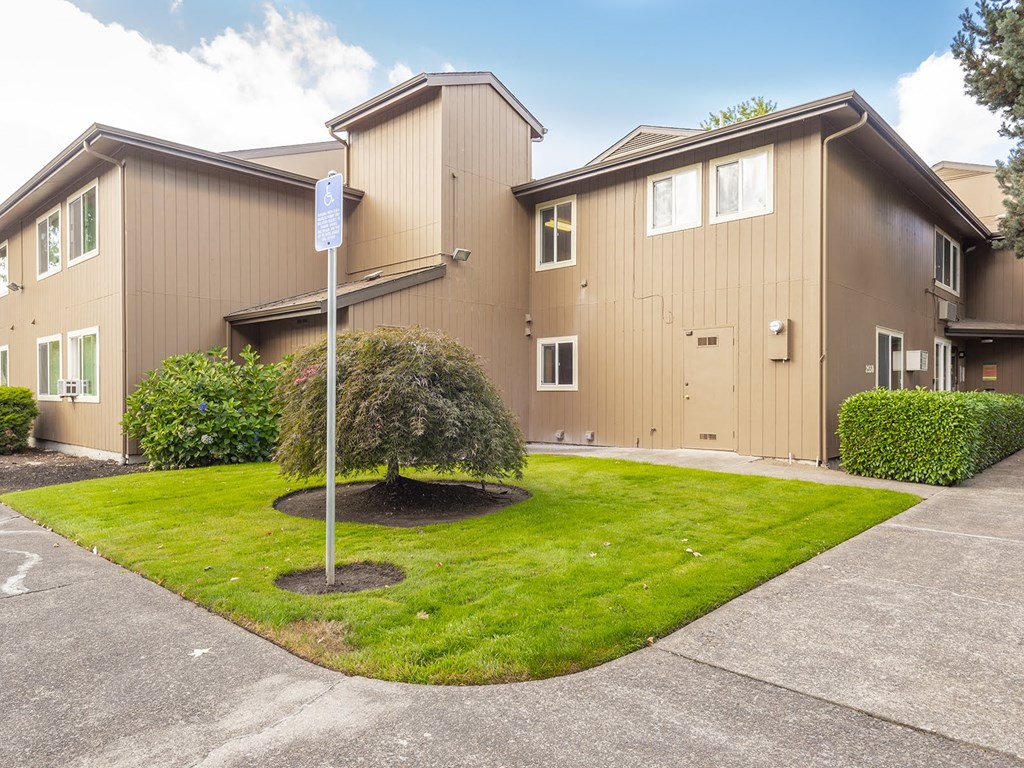 the front of a house with a lawn and a street sign