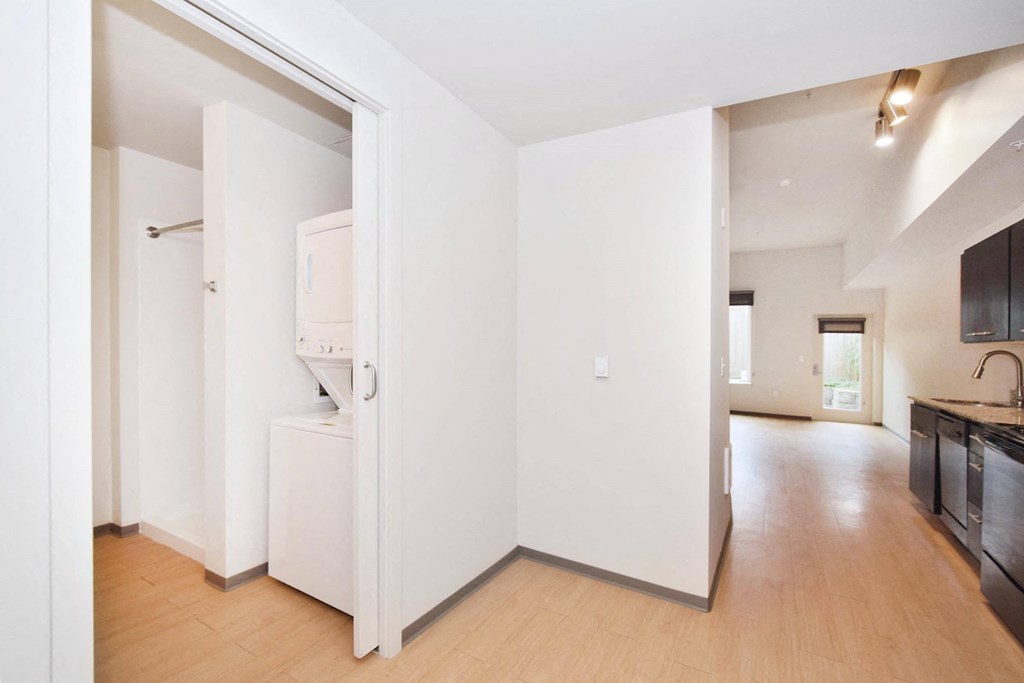a bedroom with a medium hardwood floor and a closet with a washer and dryer