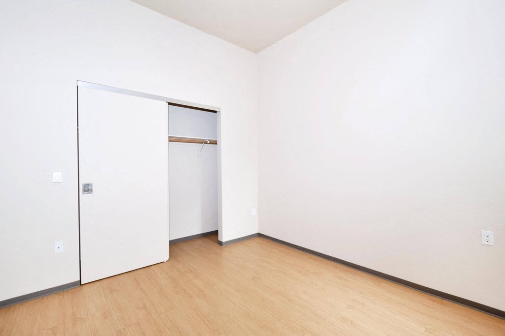 a bedroom with white walls and a wooden floor