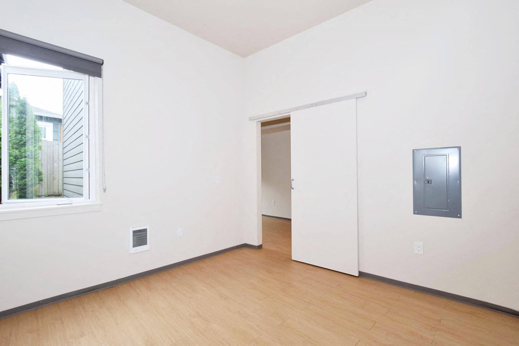 a bedroom with white walls and wood floors