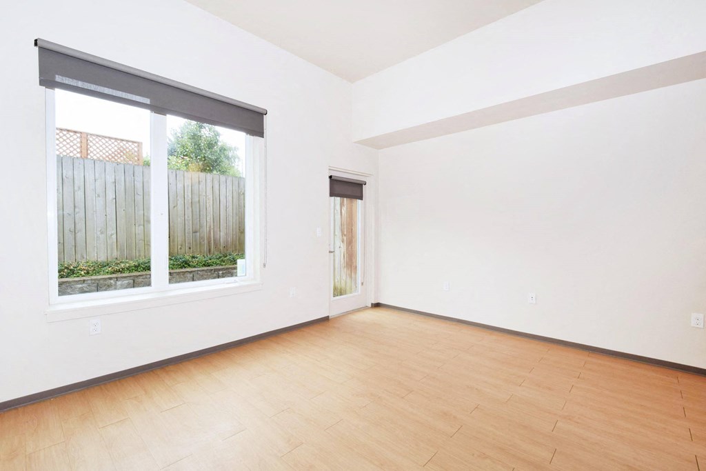 a bedroom with a large window and hardwood floors