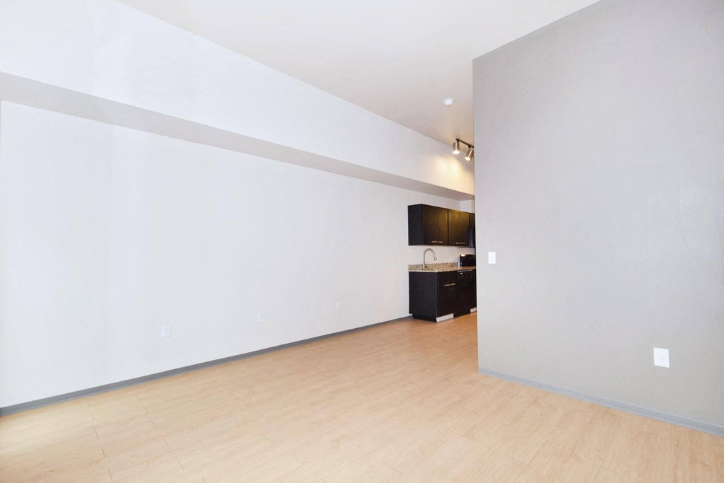a bedroom with a large white wall and a wooden floor