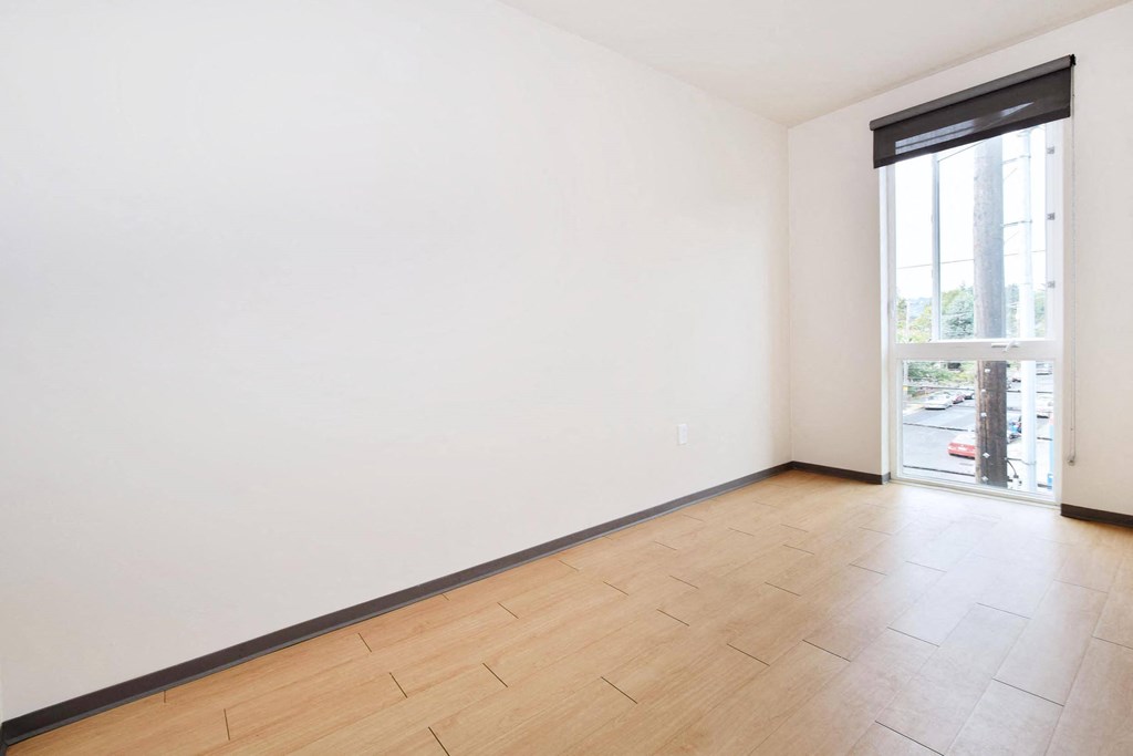 a bedroom with a large window and hardwood floors