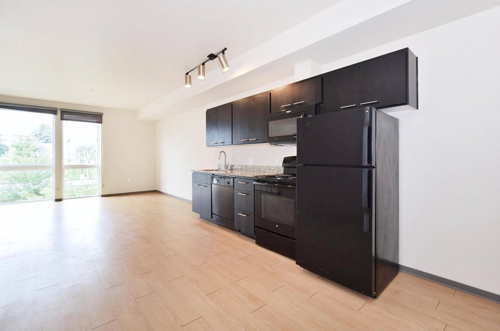 a kitchen with black cabinets and a wooden floor