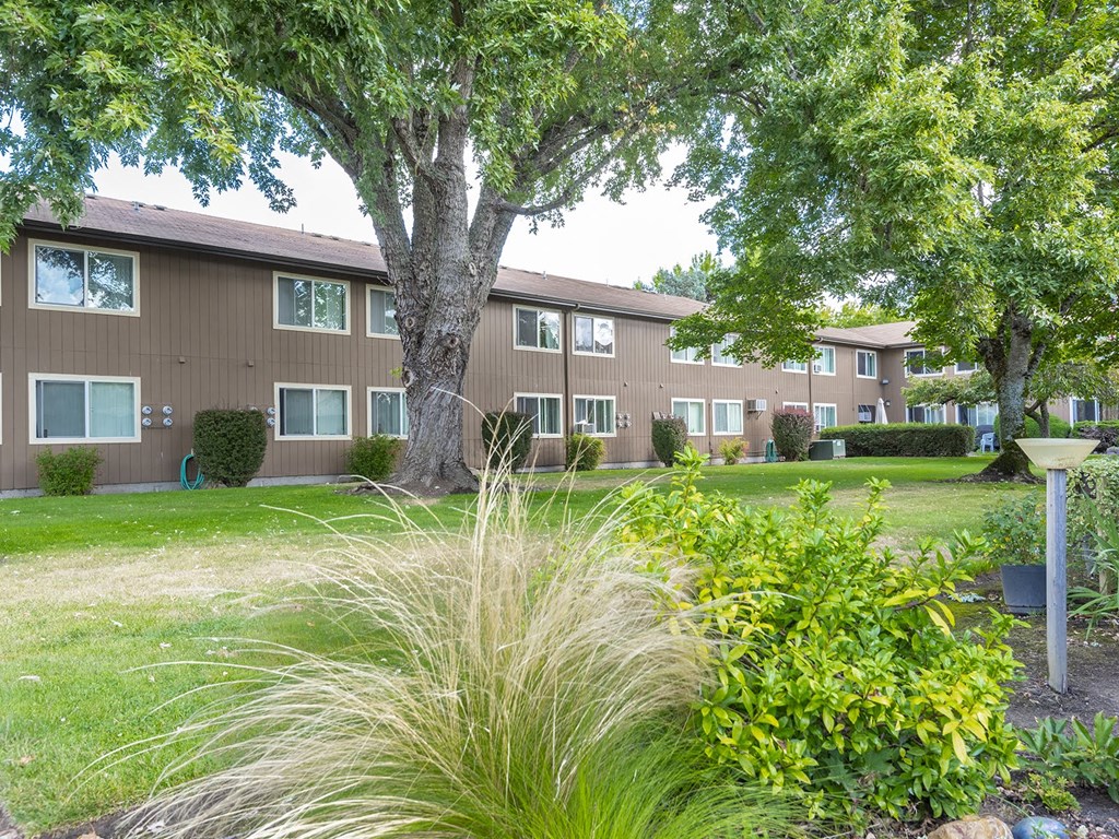 an apartment building with a lawn and trees