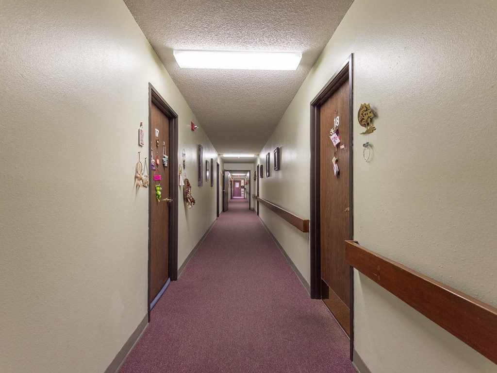 a hallway with doors and a pink carpeted floor