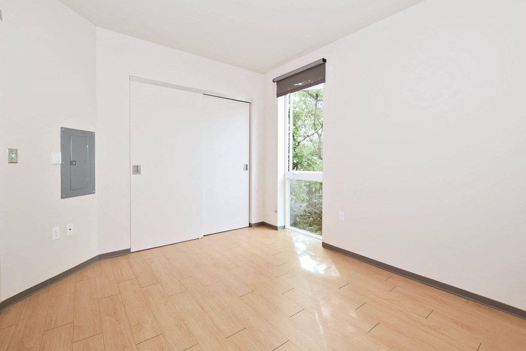 a bedroom with hardwood floors and white walls
