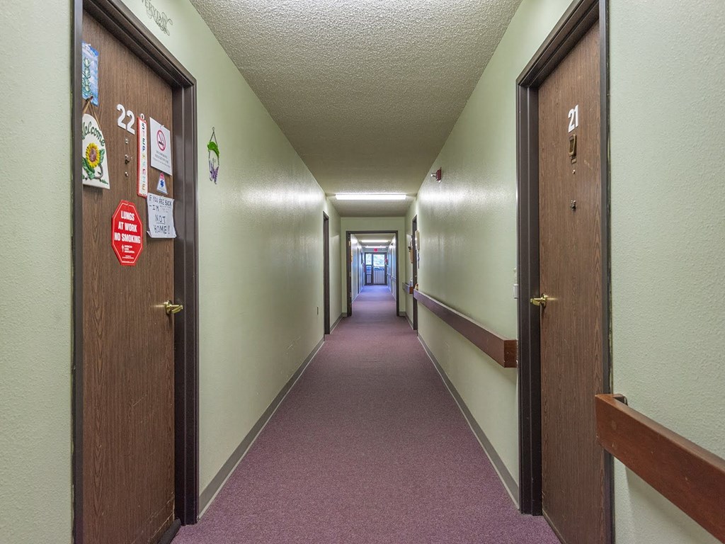 a hallway with doors and signs on the walls and a pink carpet