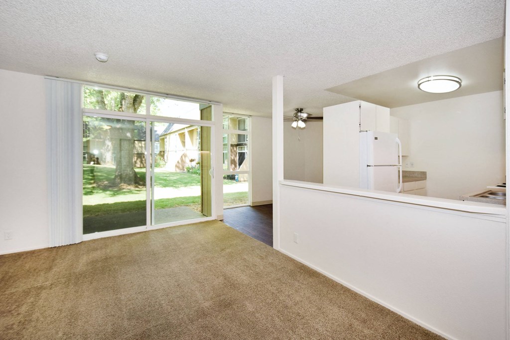 a living room with a large window and a door leading to a kitchen