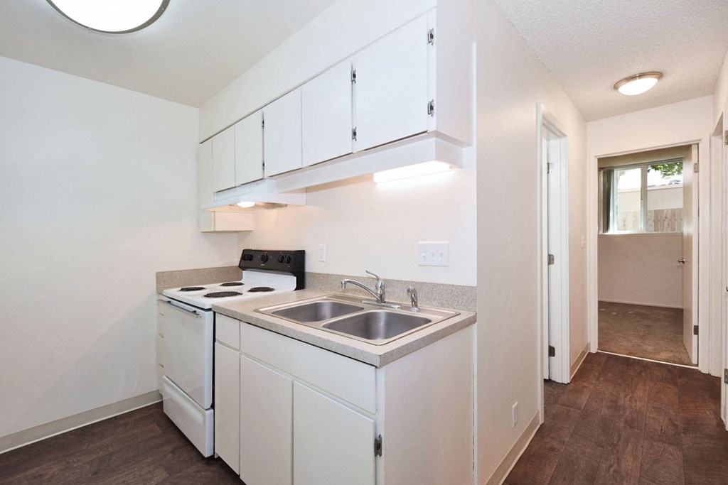 a small kitchen with white cabinets and a stainless steel sink