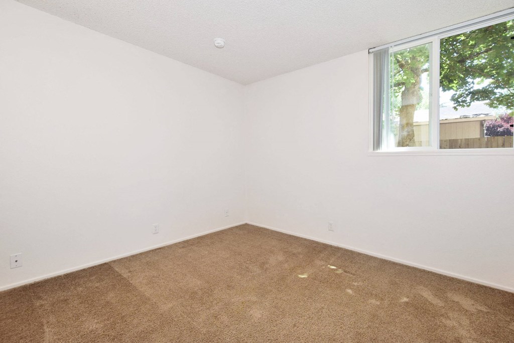 a bedroom with white walls and a window