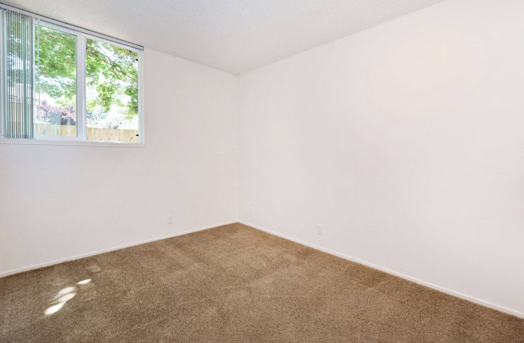 a bedroom with white walls and a window