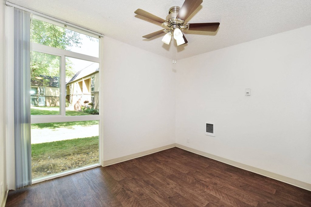 a bedroom with a large window and a ceiling fan