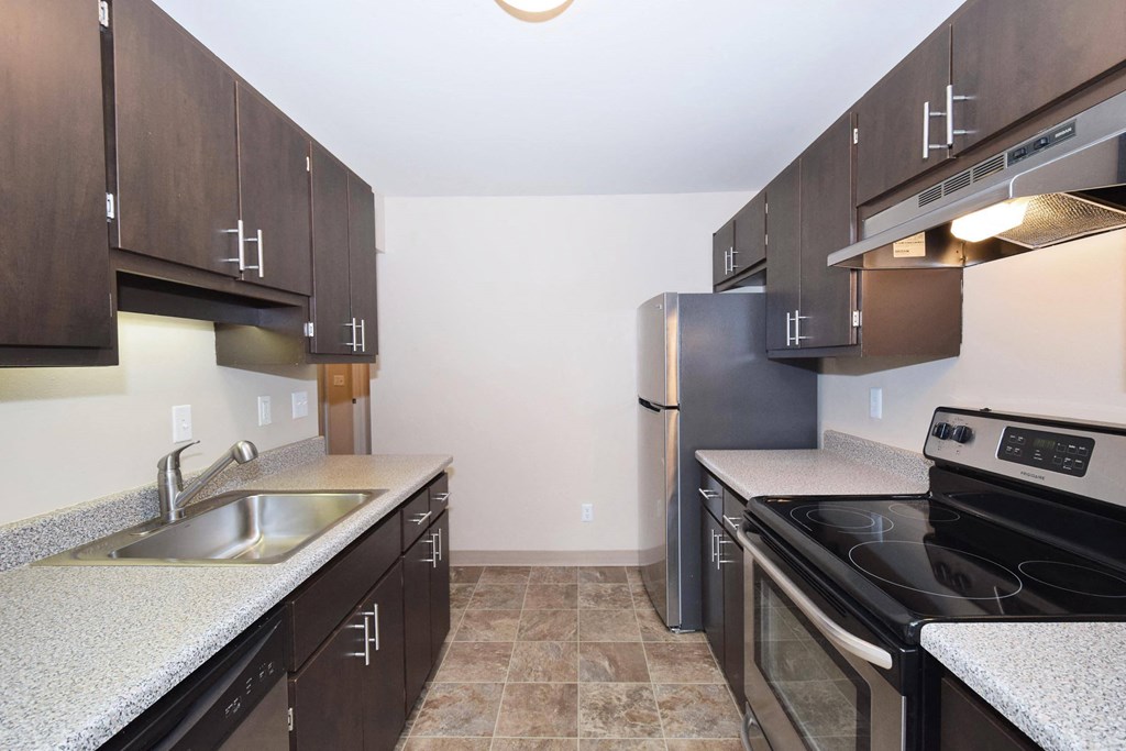 a kitchen with dark cabinets and white countertops