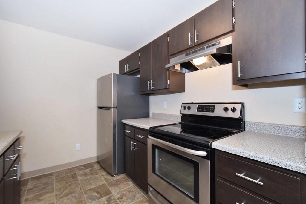 a kitchen with dark cabinets and stainless steel appliances