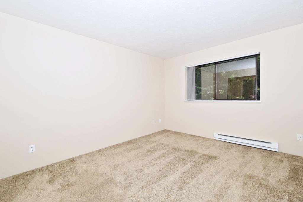 a bedroom with a large window and beige carpet