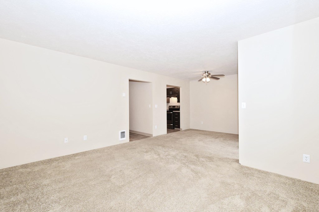 an empty living room with a ceiling fan