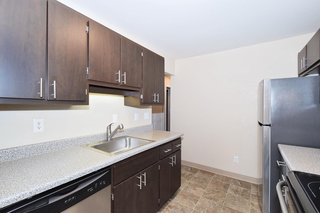 a kitchen with wooden cabinets and a stainless steel refrigerator