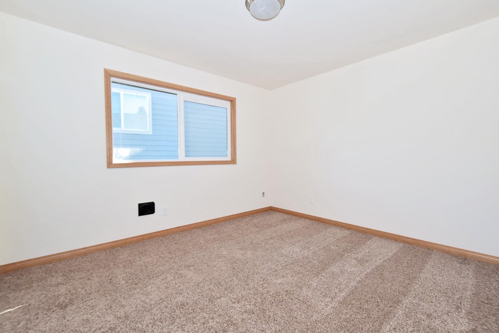 a bedroom with white walls and a large window