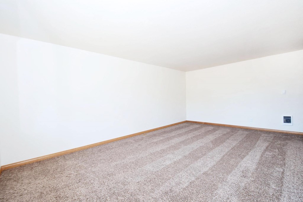 a bedroom with white walls and a beige carpet