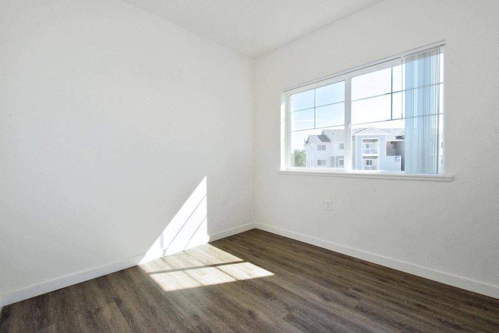a bedroom with hardwood floors and a large window