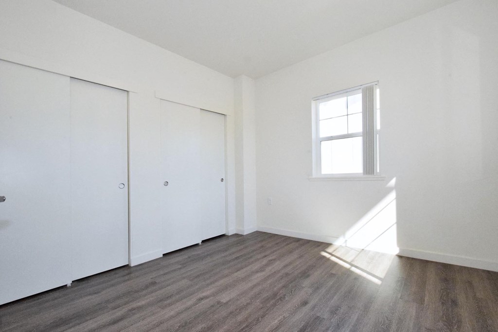 an empty room with white walls and a window and wooden floors