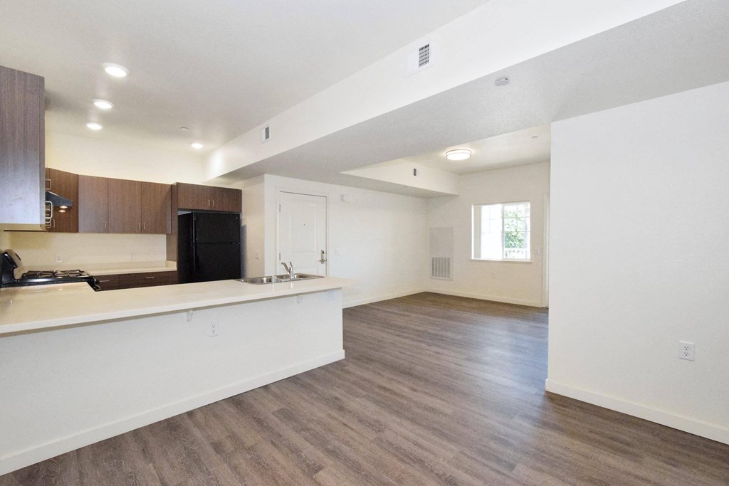 an empty living room and kitchen with white walls and wood flooring