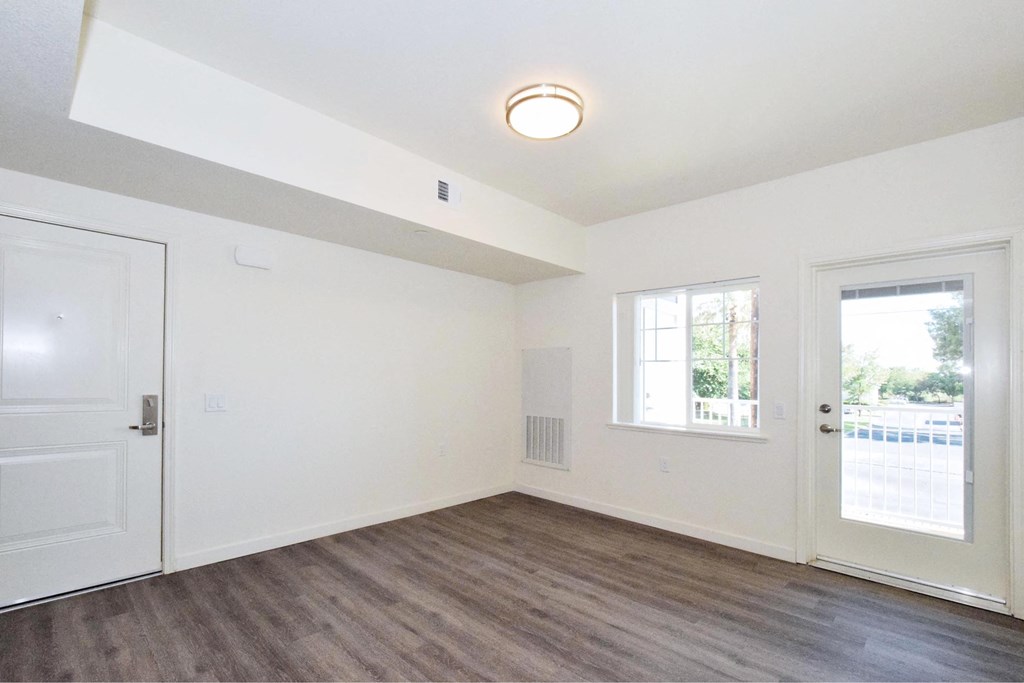 the living room of an empty house with white walls and wood floors